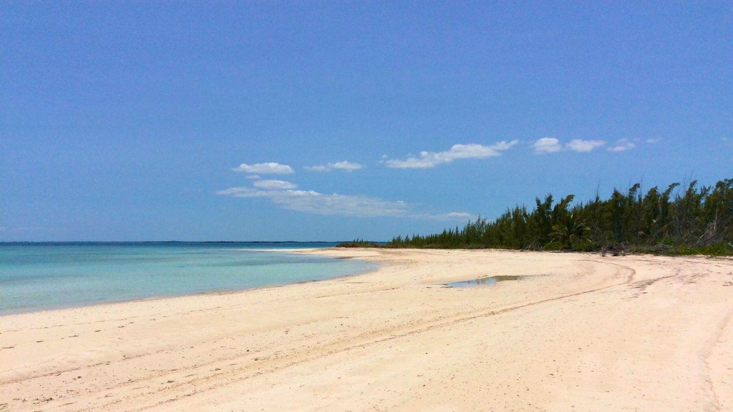 A long empty beach curving along a northern Abaco cay