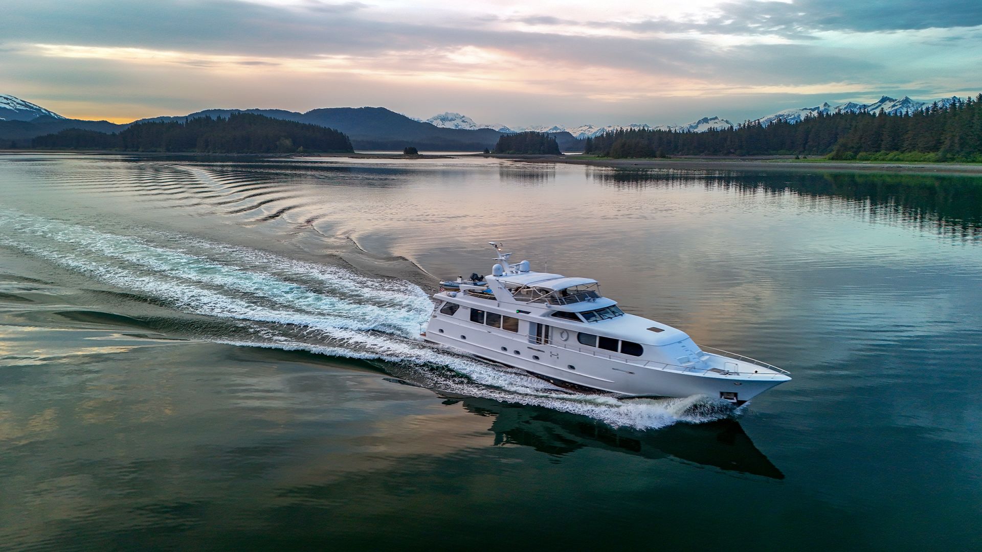 The yacht on a pastel dusk run between darkening ridgelines.