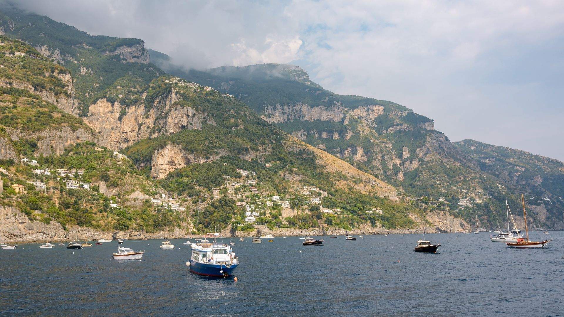 Crewed sailing catamaran under canvas off the Amalfi Coast