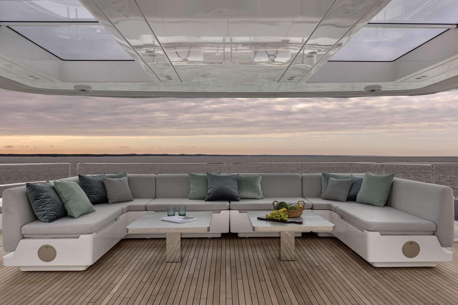 Aft-deck cushion lounge under the bimini at sunset on a crewed catamaran