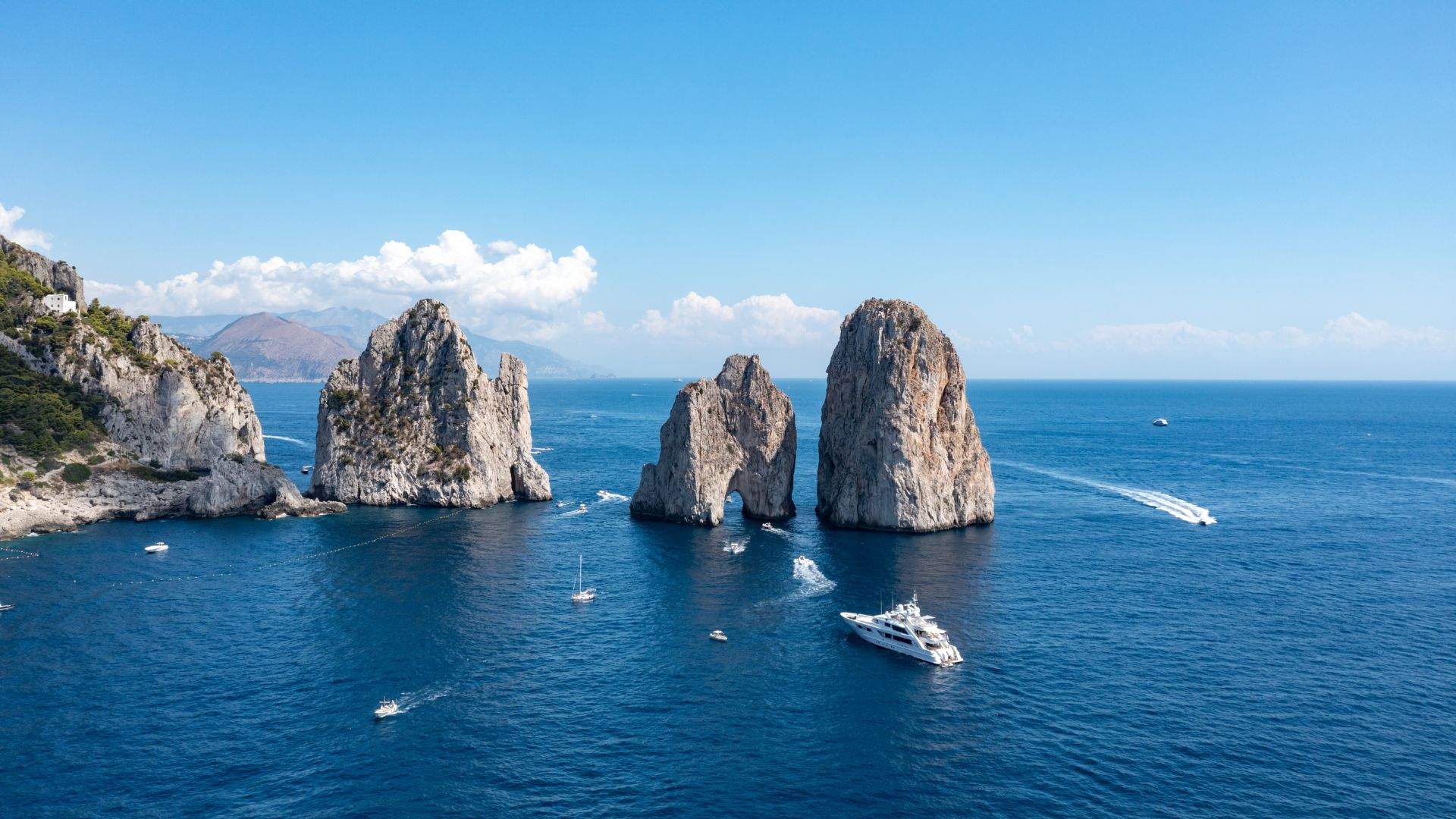 Crewed motor yacht anchored off Capri's Faraglioni rocks