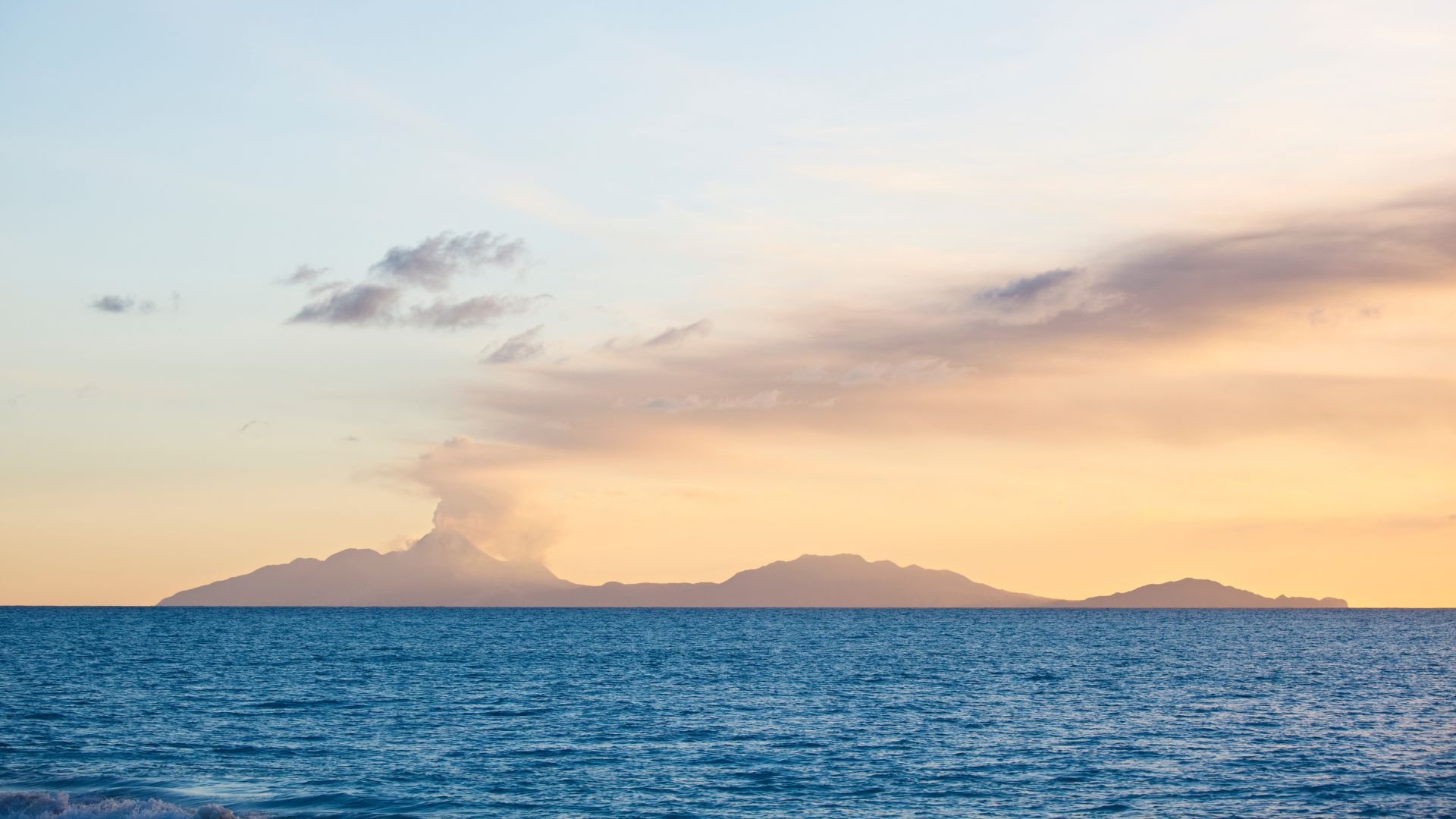 The Soufrière Hills volcano on Montserrat rising from the sea, an ash plume drifting from the summit