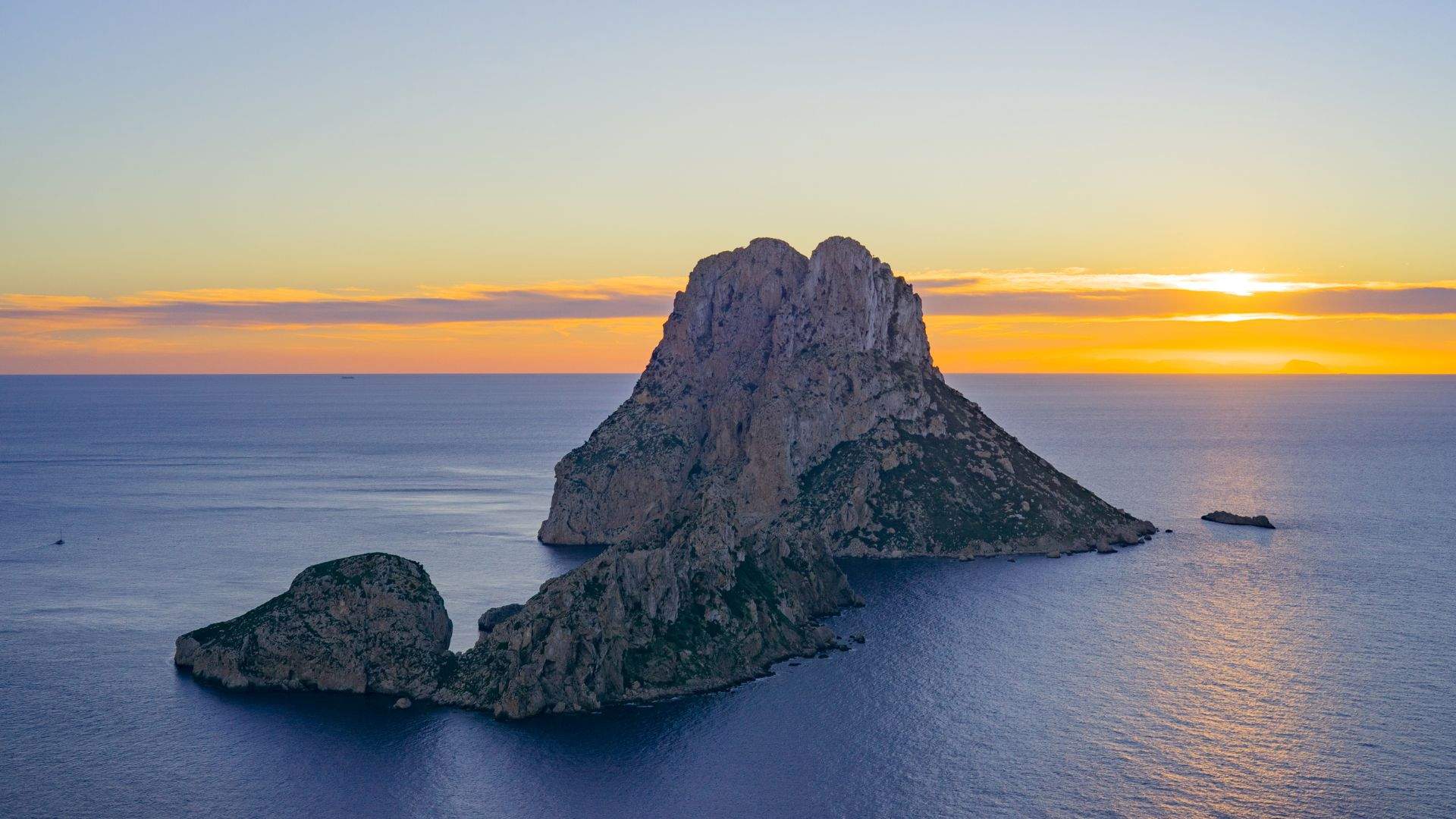 The 413-meter Es Vedrà cliff-stack from a yacht anchored off Cala d'Hort at sunset.