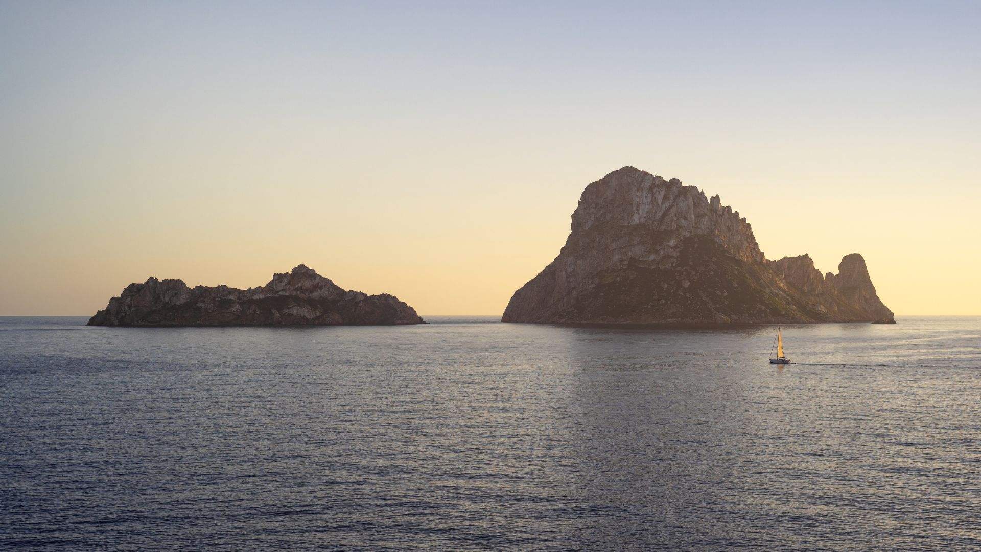 The offshore cliff-stack at Ibiza's southwest corner — uninhabited, dramatic, the half-hour of sunset behind it the visual signature of an Ibiza charter.