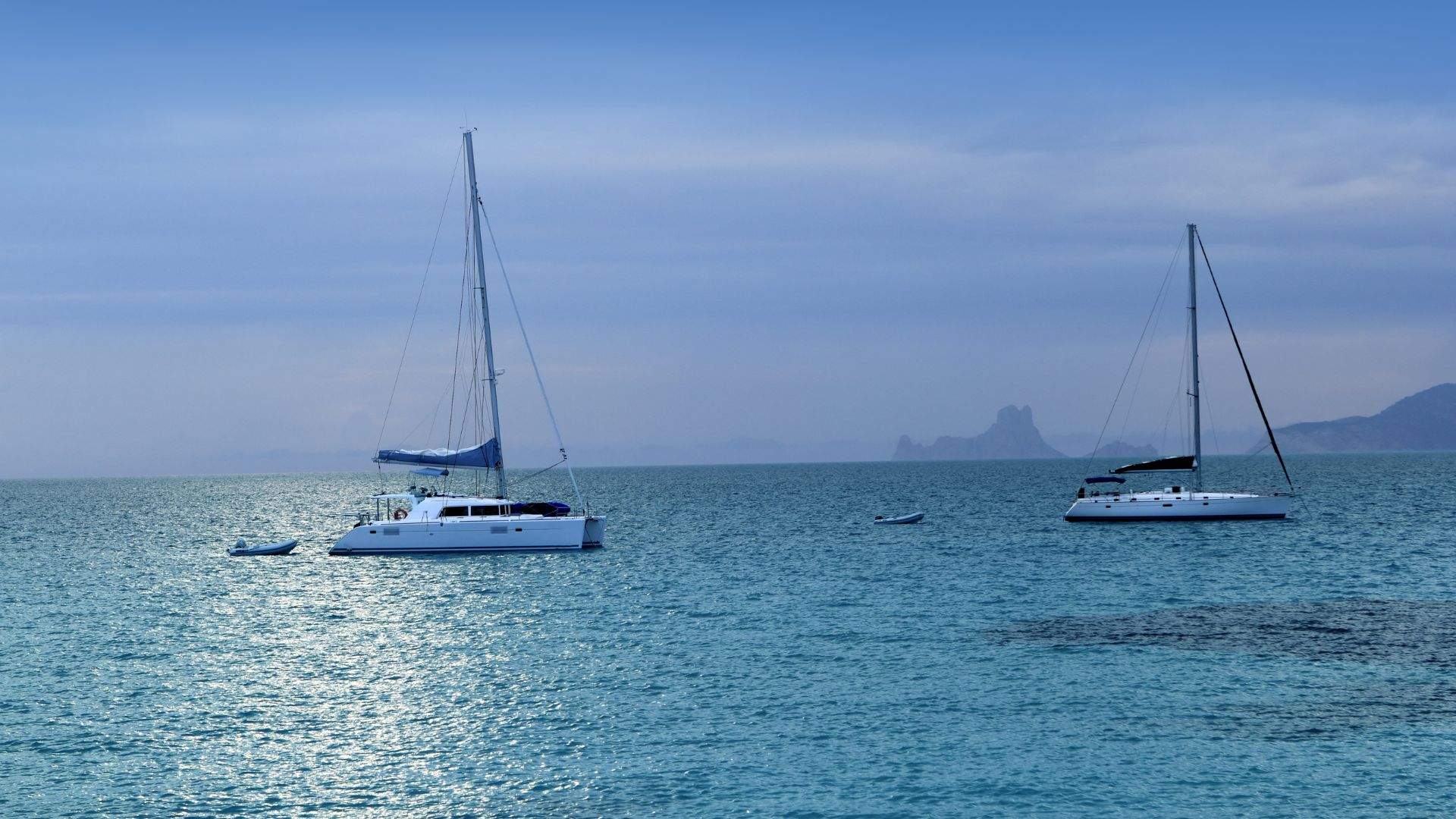 Motor yacht at anchor off Formentera's Ses Illetes, tender approaching the Juan y Andrea pontoon