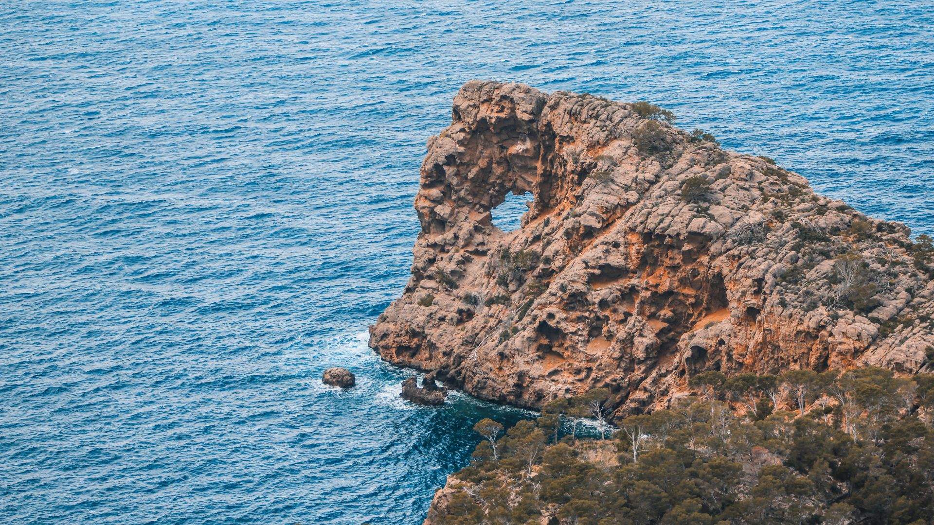 Sa Foradada rock peninsula with tender approaching from anchored yacht — Mallorca's Tramuntana coast.