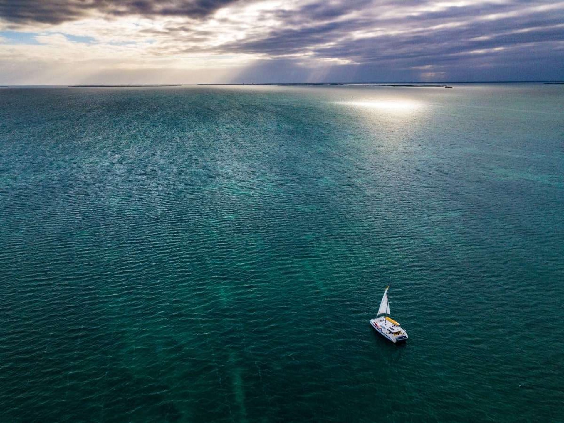Catamaran under sail on a dramatic open-water Belize crossing.