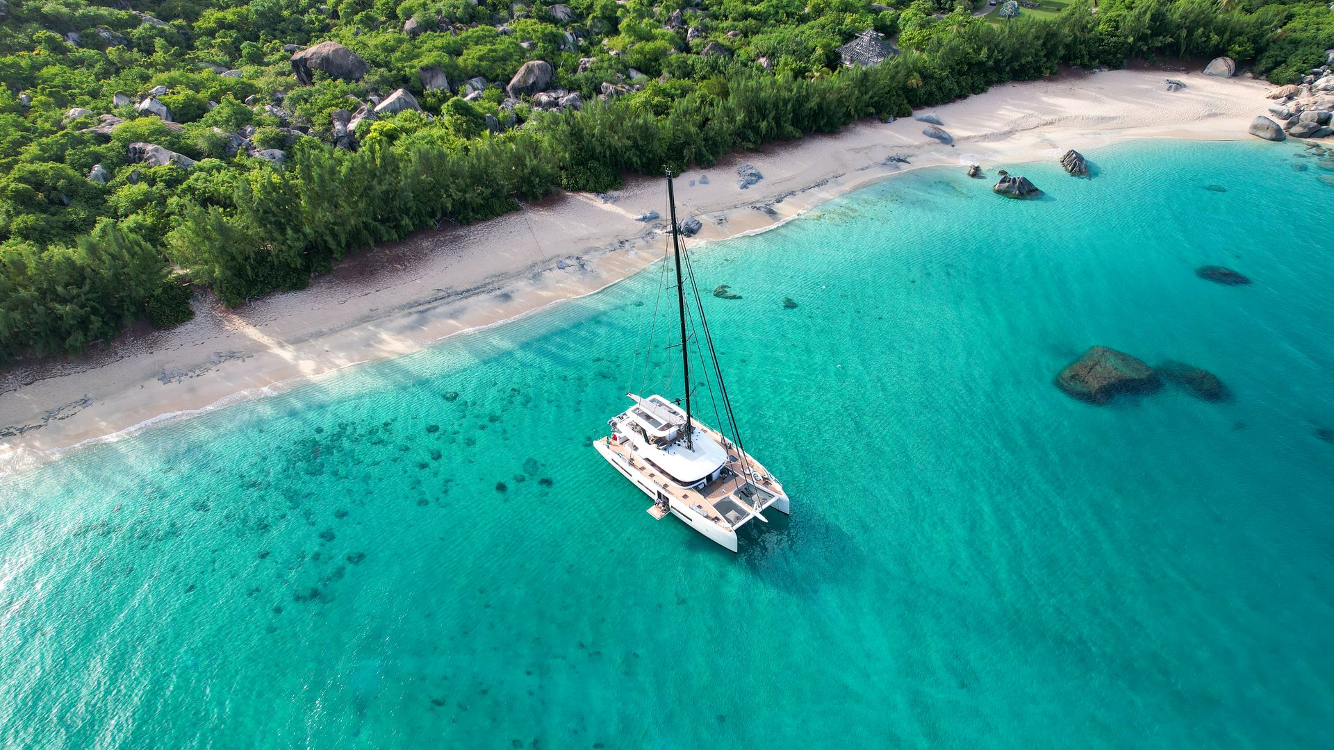 A crewed catamaran anchored off the beach at Valley Trunk Bay, Virgin Gorda.