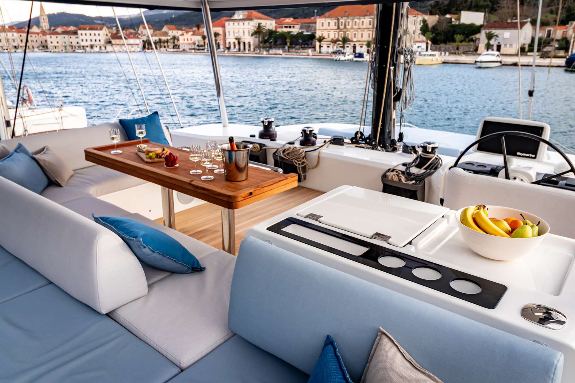 Cockpit dining aboard a crewed catamaran with a Dalmatian coastal town across the water