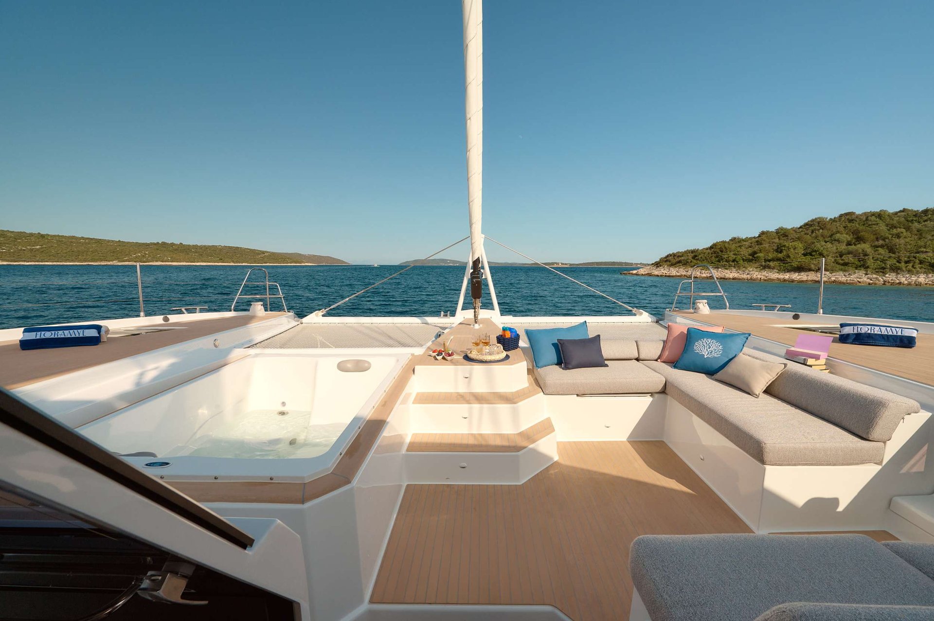 The bow lounge of a crewed charter yacht at anchor in a Dalmatian cove.