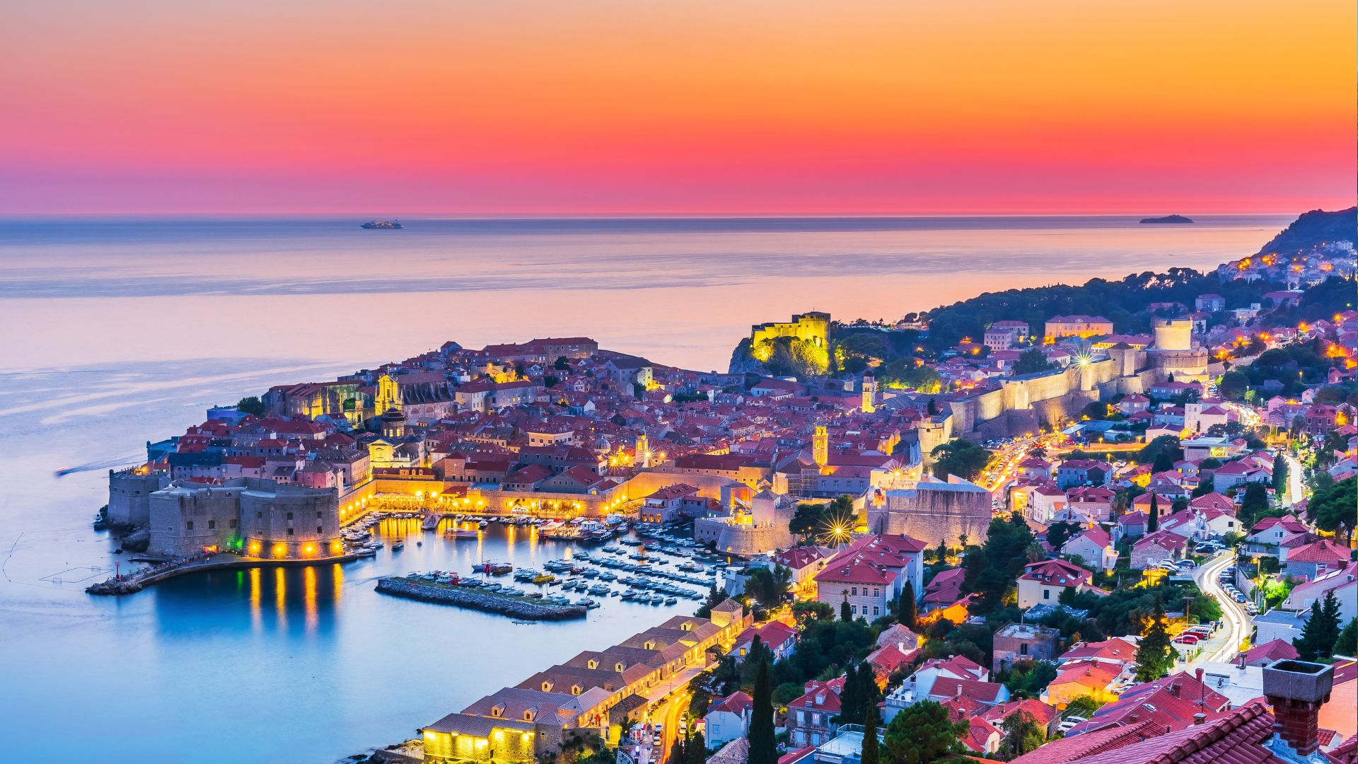 The walls of Dubrovnik glowing at sunset above the Adriatic.
