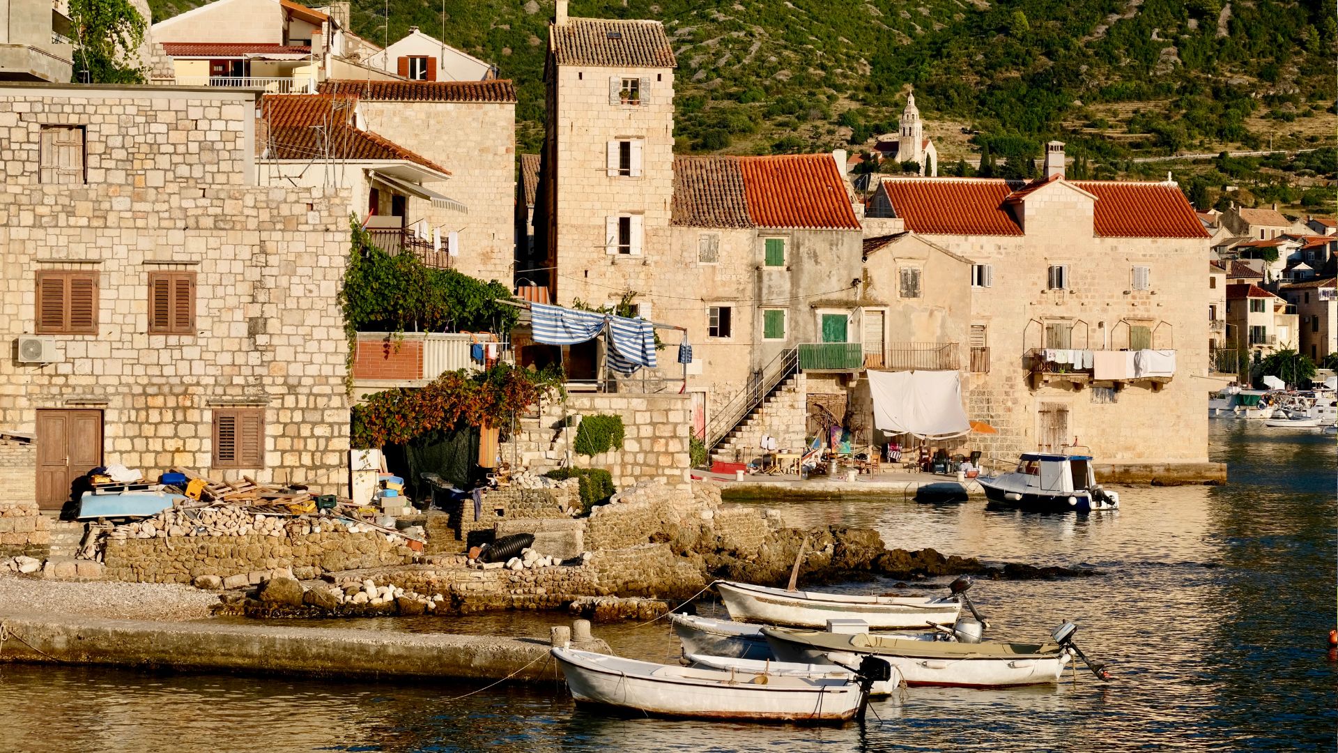 The harbor of Komiža on Vis with stone houses stacked above the quay.