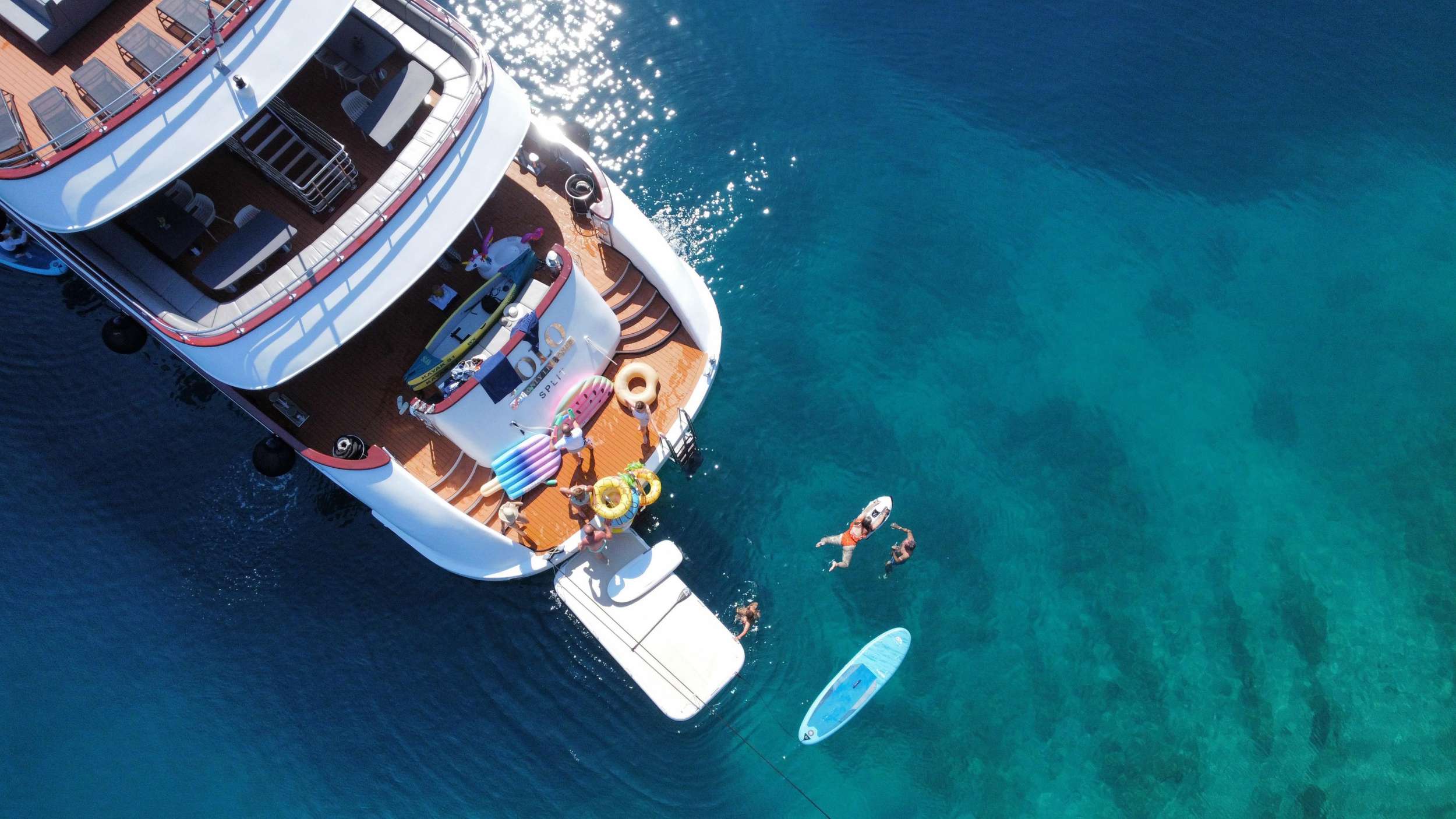 Guests swimming off a crewed charter yacht on the Dalmatian coast.