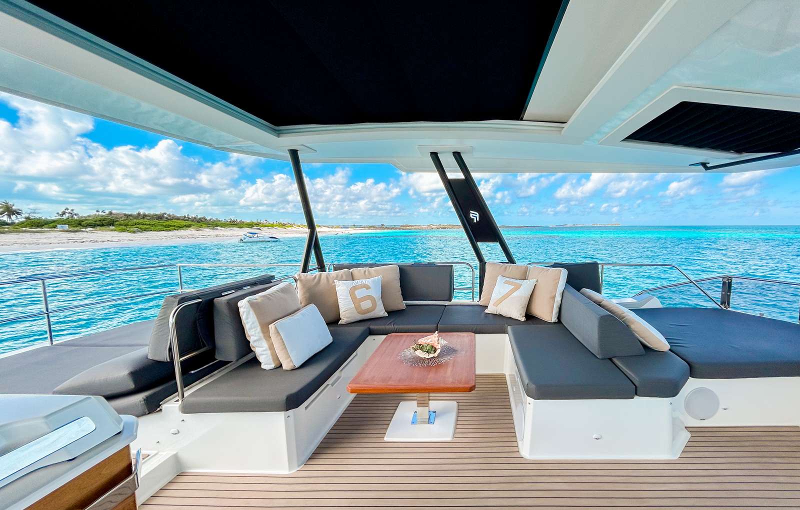 Cockpit lounge of a crewed catamaran with a Bahamas beach behind