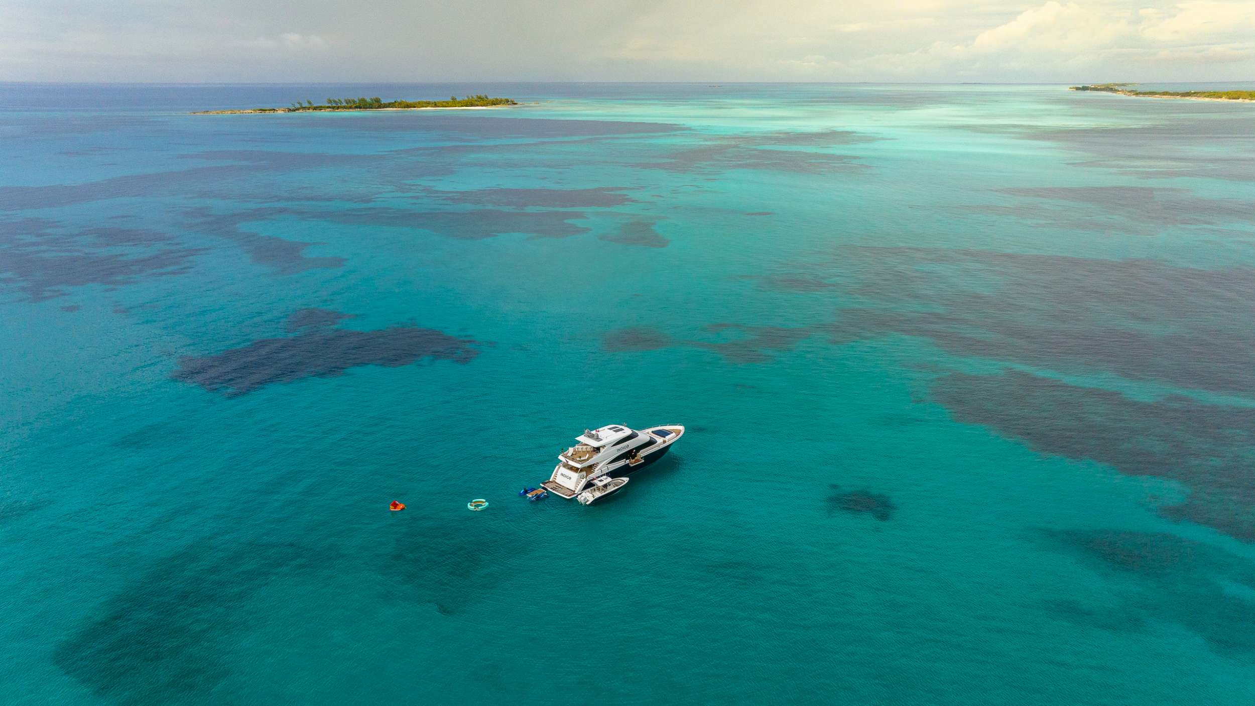 Aerial view of a crewed motor yacht anchored in the Exuma Cays