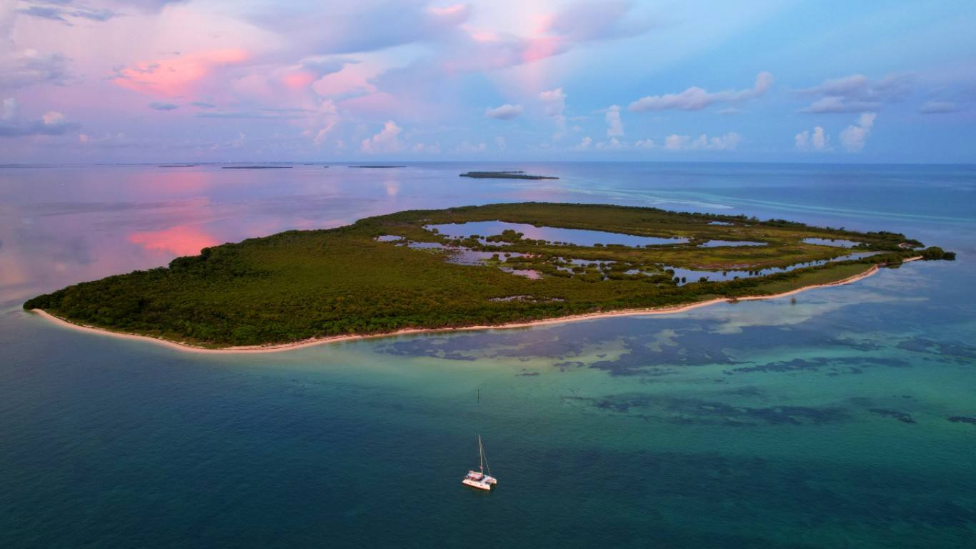 Aerial of a mangrove key on the Gulf side with a small catamaran anchored off its beach
