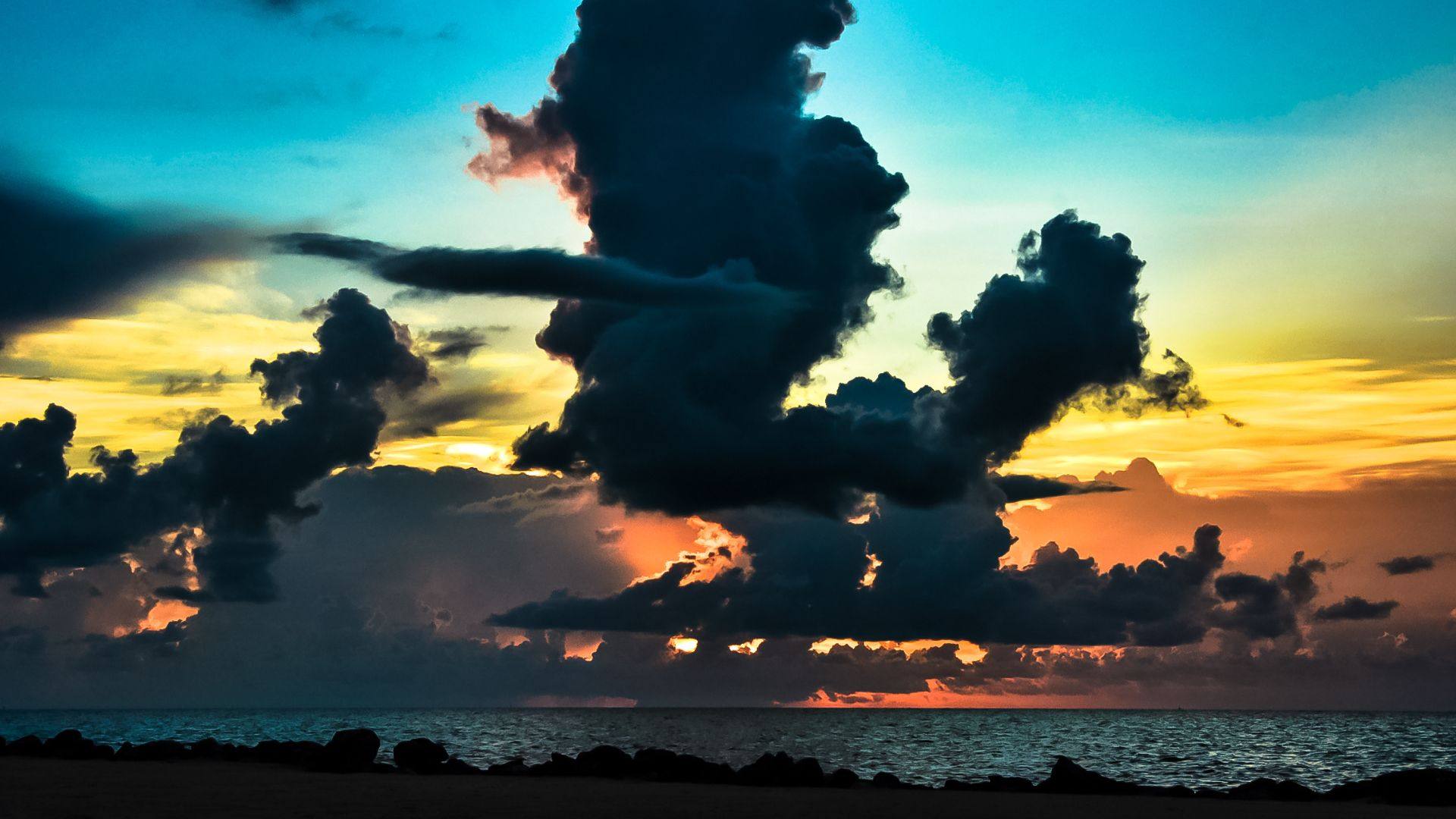 Towering clouds over an orange-and-teal Gulf sunset.