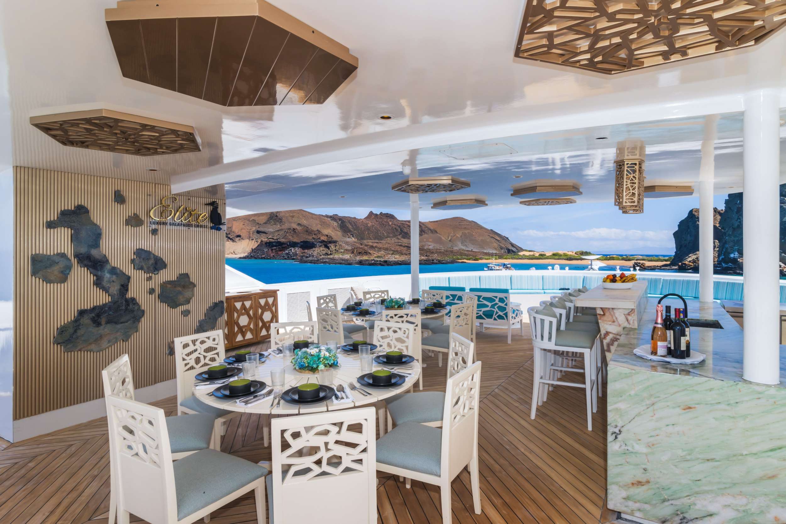 Aft-deck dining table set for the group with a volcanic islet visible through the open side