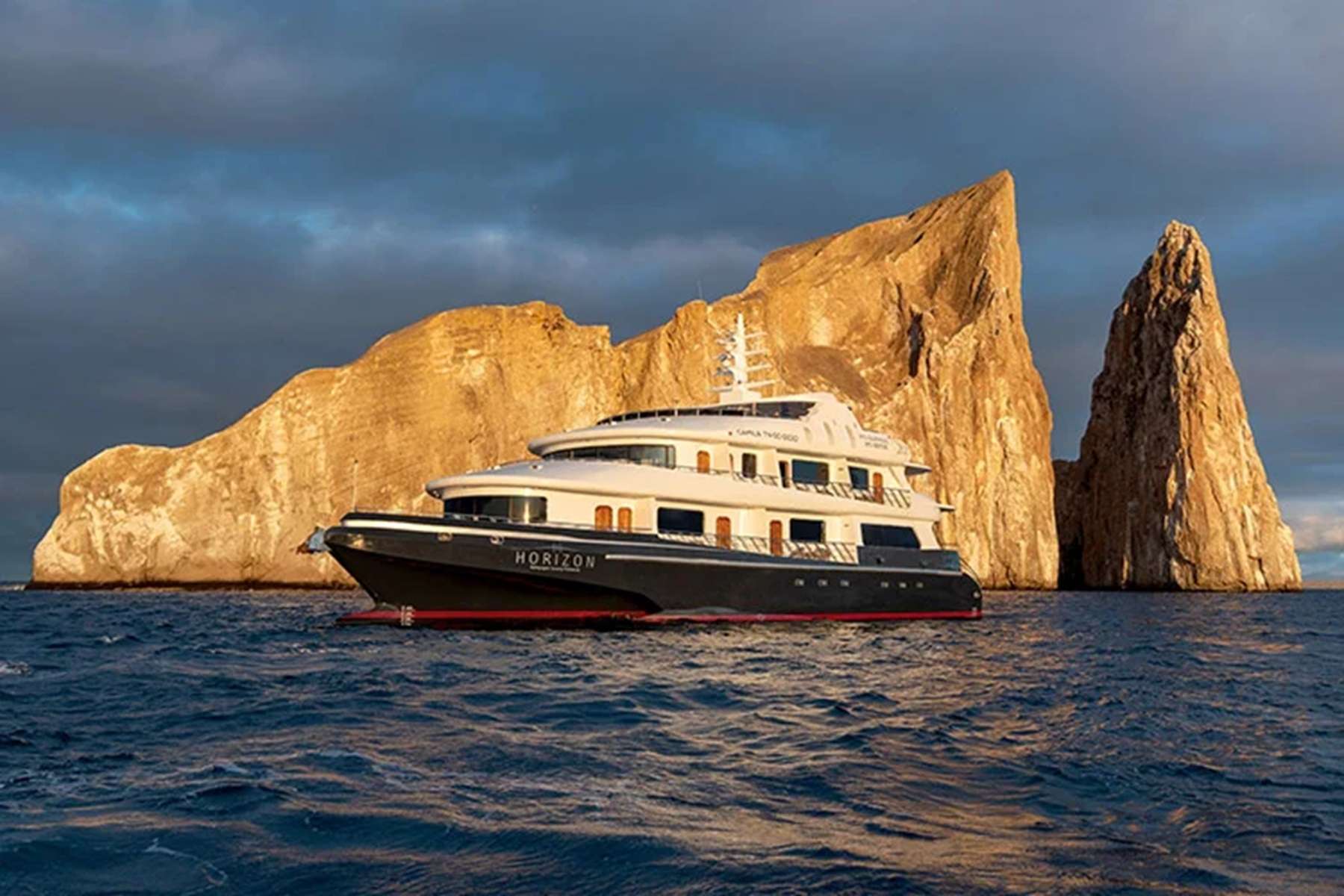 Expedition yacht at anchor in front of Kicker Rock at sunset, San Cristóbal