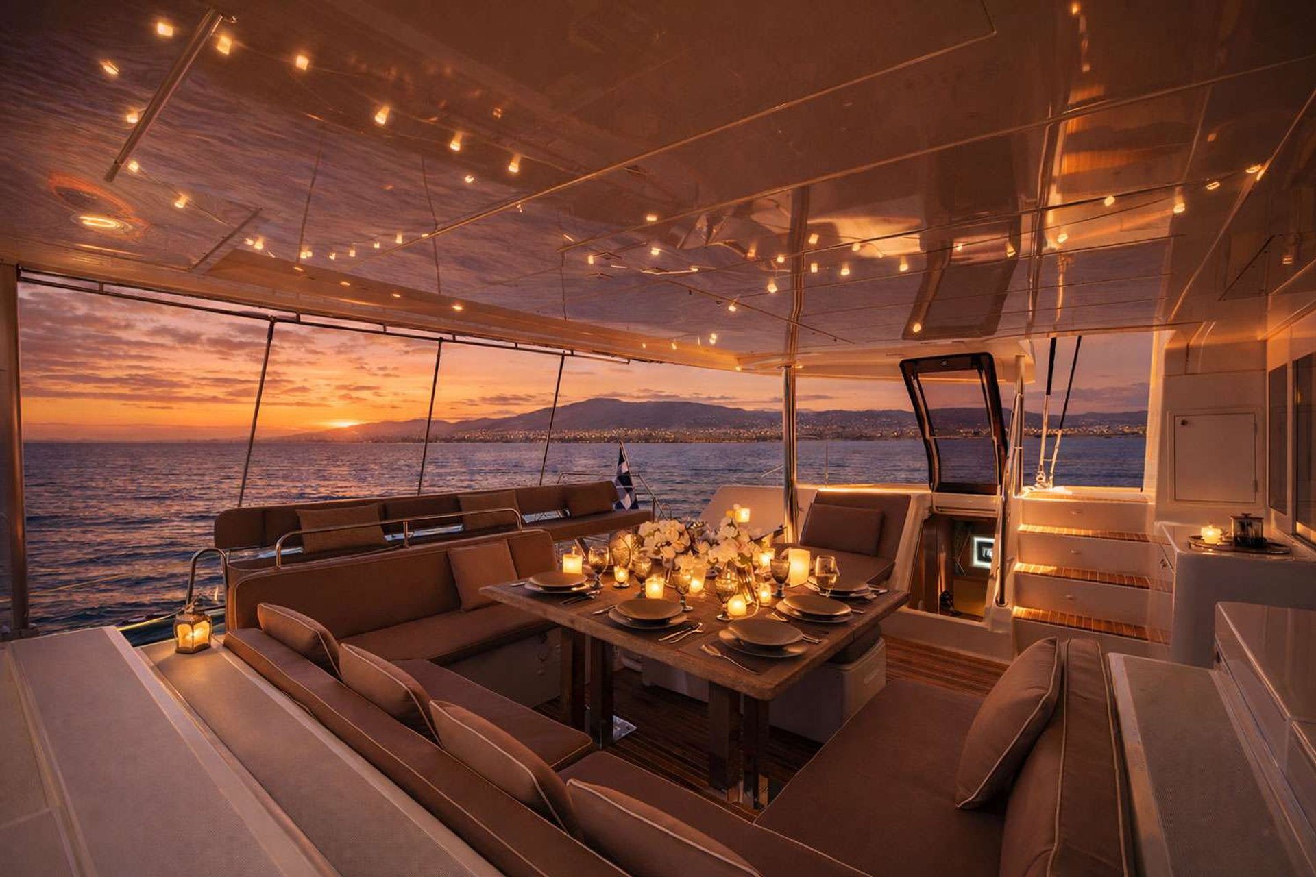 Evening aboard—fairy lights across the cockpit, chef's plating coming out, the Aegean going dark to the east. Most nights of the week run to some version of this.