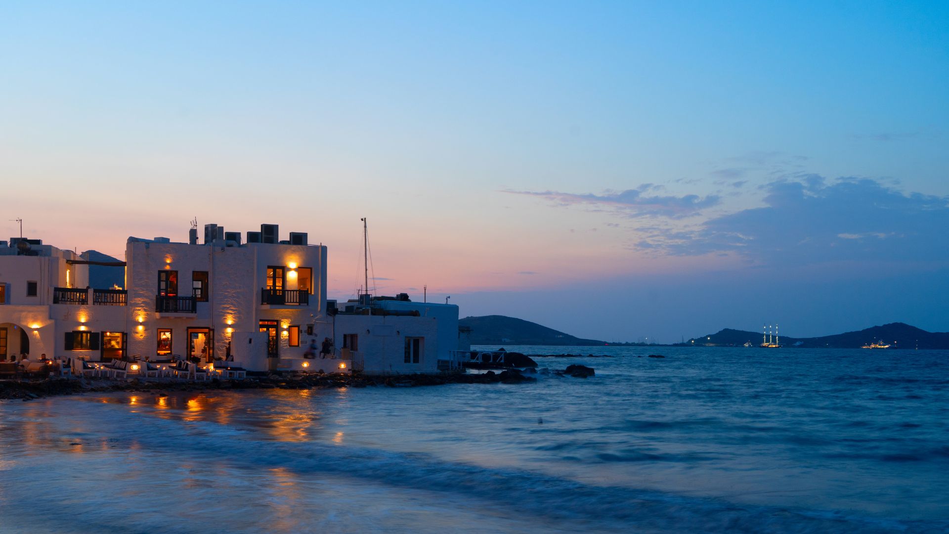 The Naoussa waterfront at dusk—stone tavernas with tables pushed right to the water, the kind of place dinner runs late.