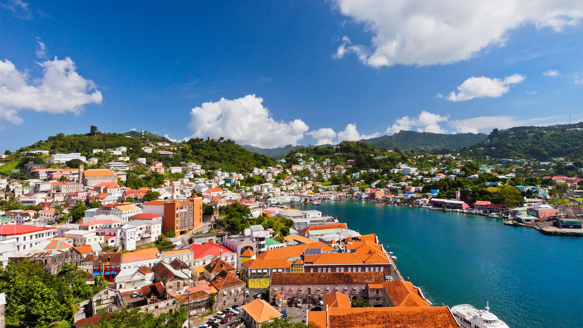 The pastel hillside town of St. George's, Grenada, with red-roofed warehouses climbing above the turquoise inner harbor.