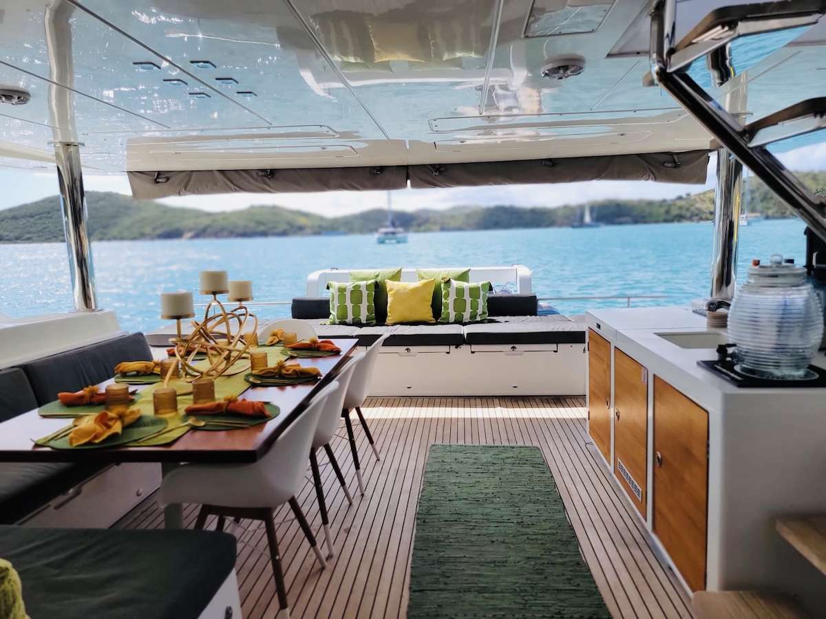 First dinner aboard at anchor in Admiralty Bay—chef's plating on the aft deck, the lights of Port Elizabeth a tender ride away across the water.
