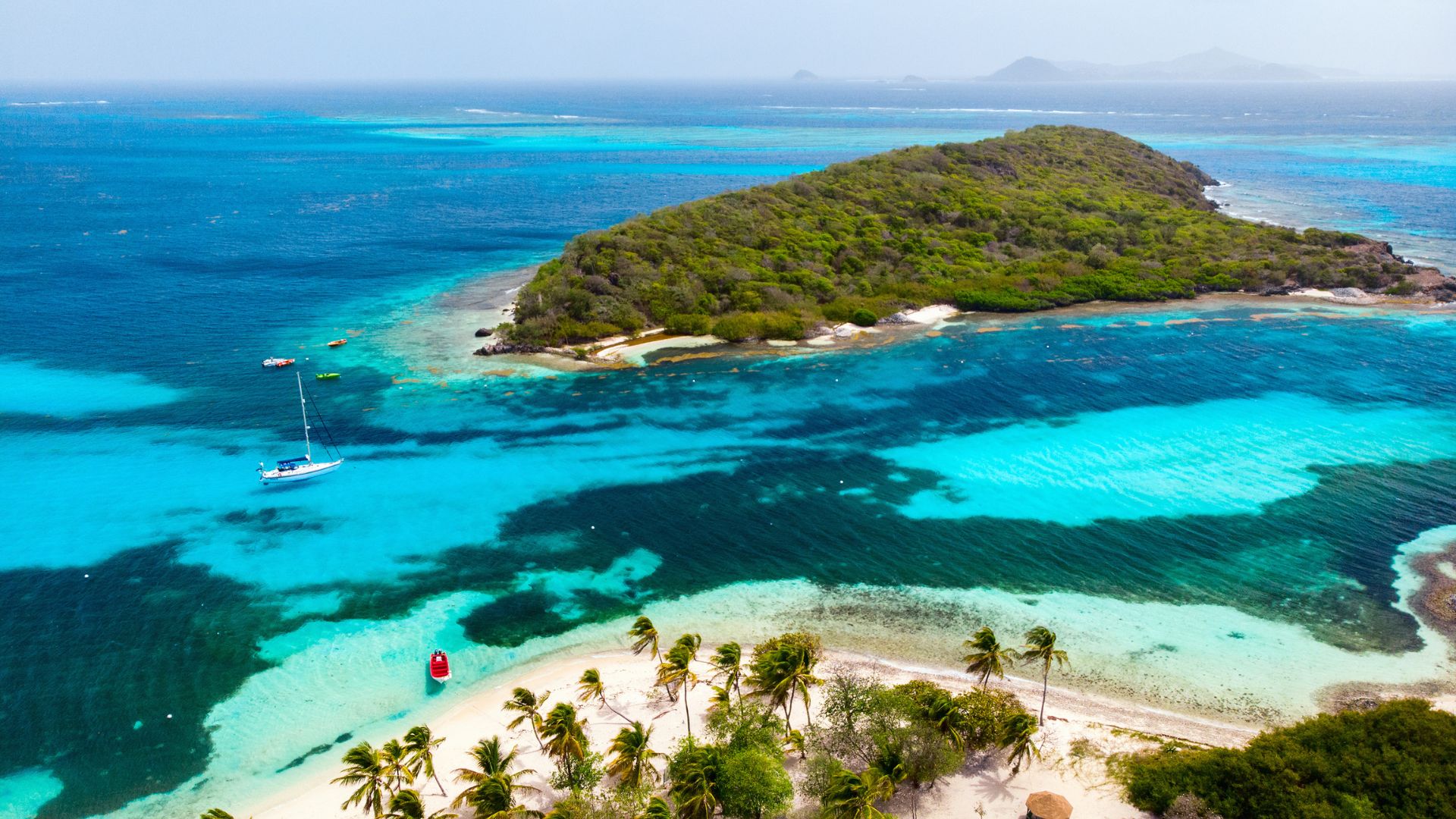 Aerial view of yachts at anchor inside the Tobago Cays Marine Park, with the Horseshoe Reef and the small uninhabited cays visible.