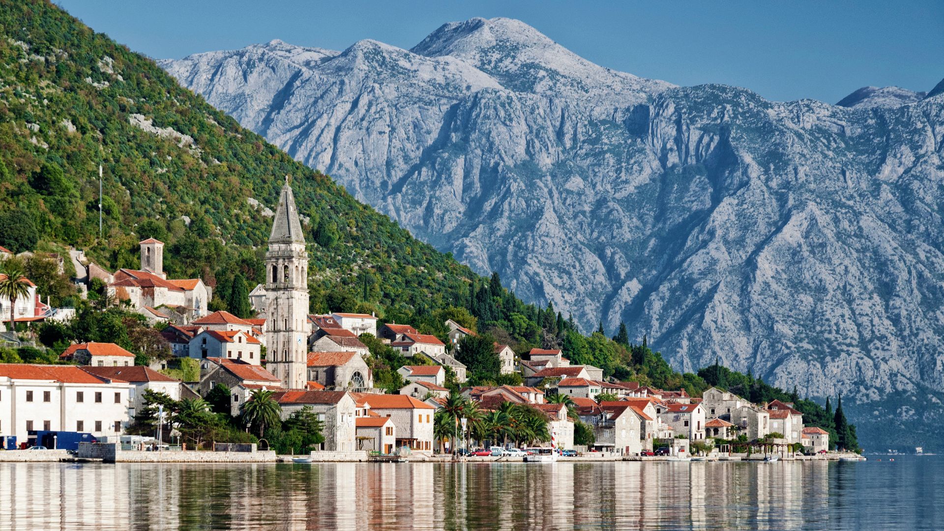 Inner Bay of Kotor light — the Lovćen wall behind Perast as the afternoon sun comes off the water. Most evenings the yacht moves between two anchorages a few miles apart.