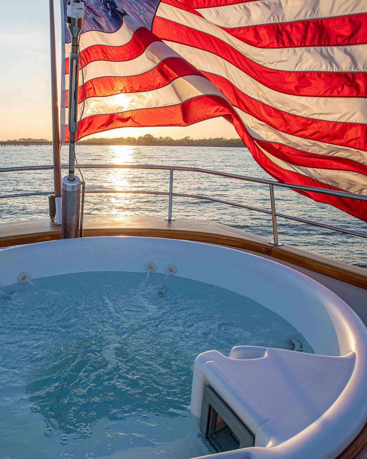 Stern Jacuzzi and American flag at sunset aboard a classic yacht on New England water