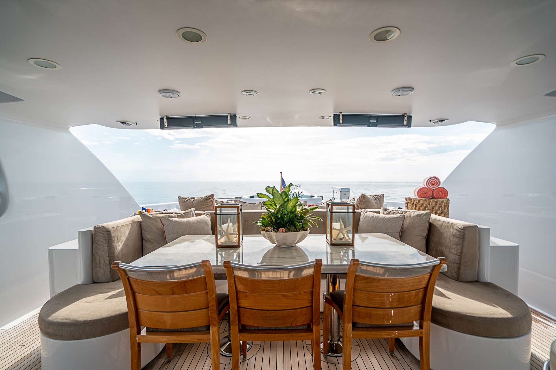 Covered aft-deck dining table aboard a crewed motor yacht, open water astern