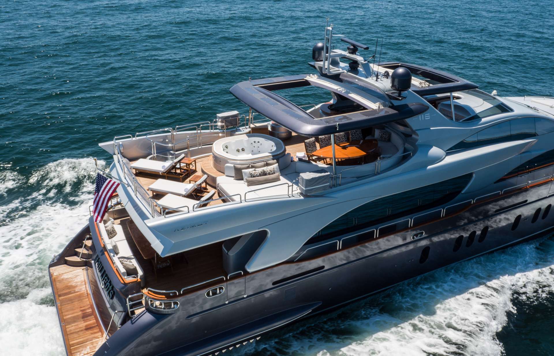 Aerial of a motor yacht under way on deep blue water, guests on the sun deck