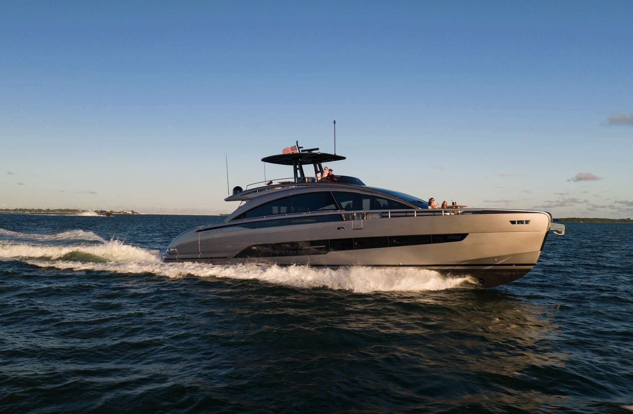 Sport motor yacht running the coast past a low green shoreline
