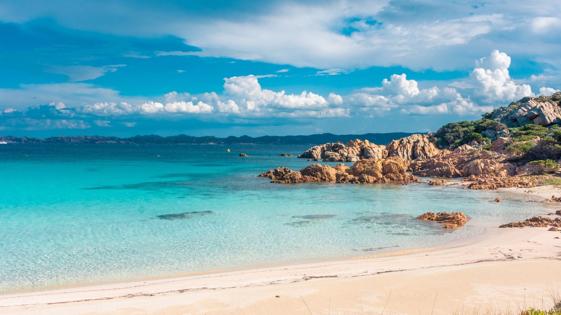 Budelli's Pink Beach — strict look-only access from offshore. The pink color comes from microscopic coral and shell fragments; visitors haven't been allowed to walk the sand since 1994.