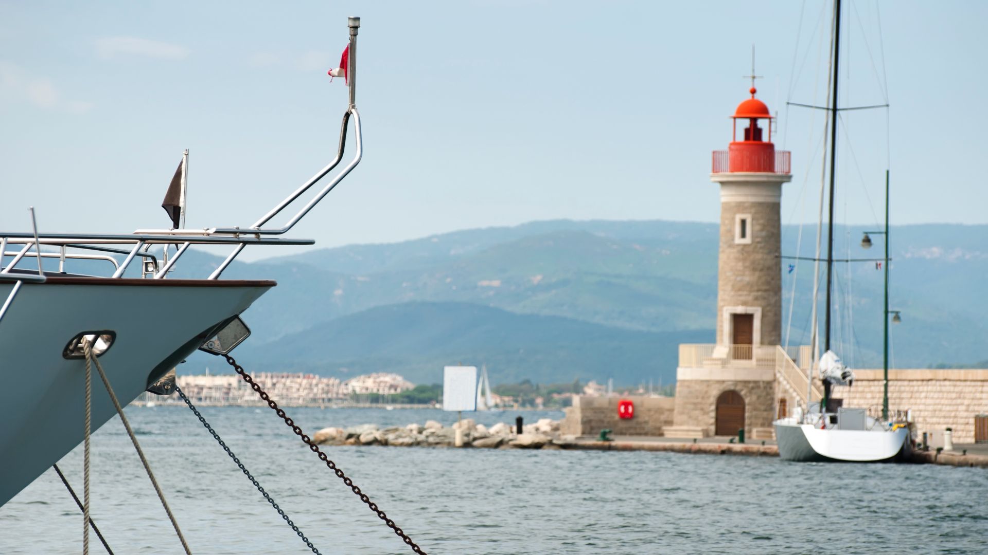 Saint-Tropez old port — pastel houses around the quay with charter yachts stern-to.