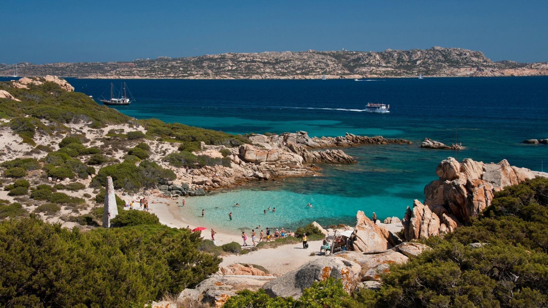 Cala Corsara on Spargi — the cove most charters anchor at for the lunch hour. Pink granite, white sand, water visibility to twenty meters.
