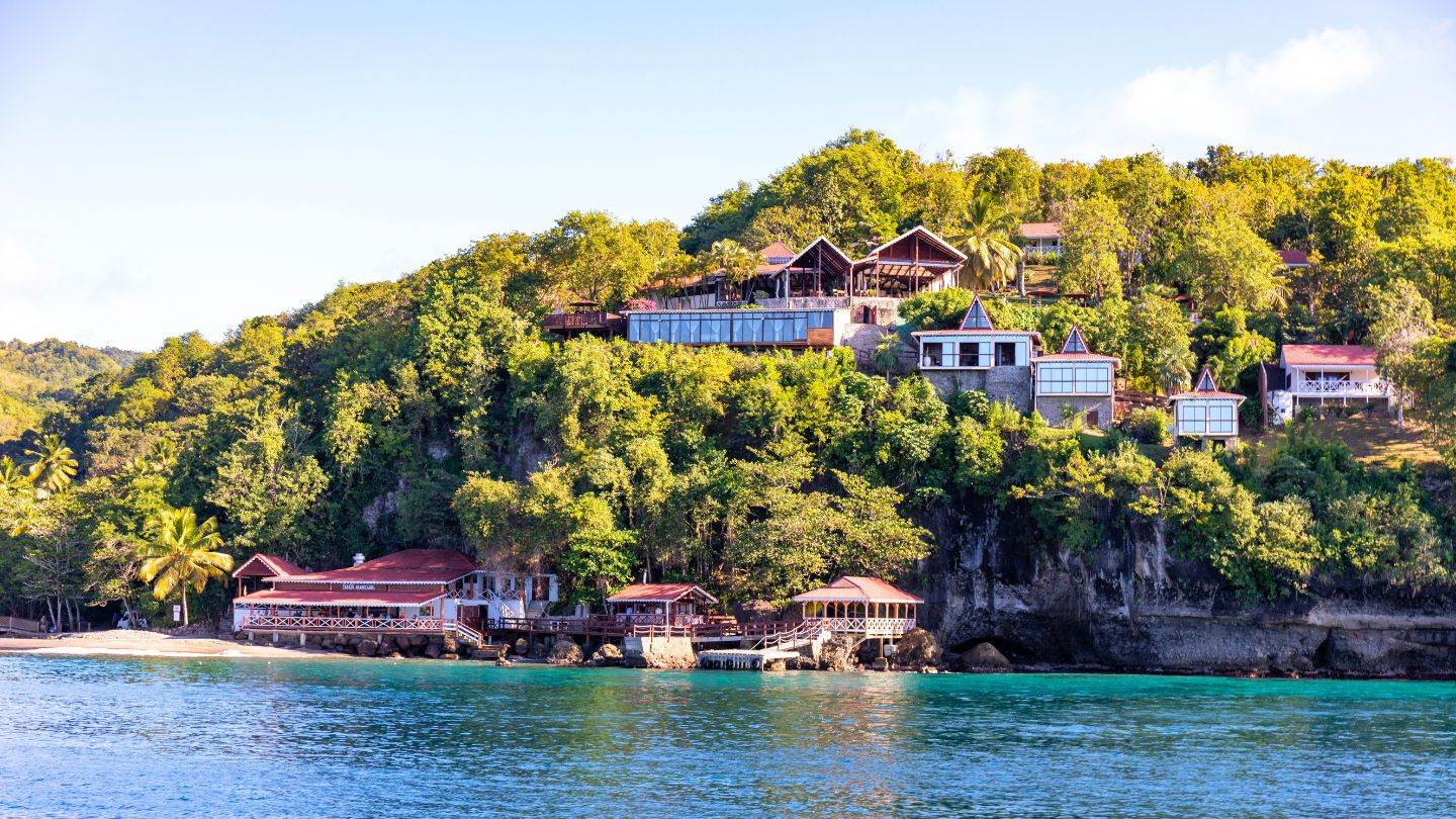 Anse Cochon from the water — the quiet cove whose reef and wreck make it the island's easiest serious snorkel.