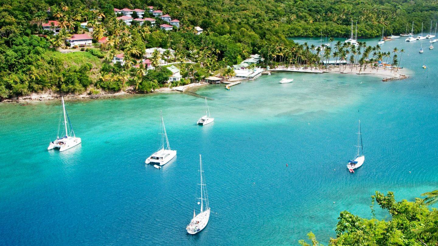 Aerial of Marigot Bay with catamarans and monohulls at anchor inside the mangrove arm