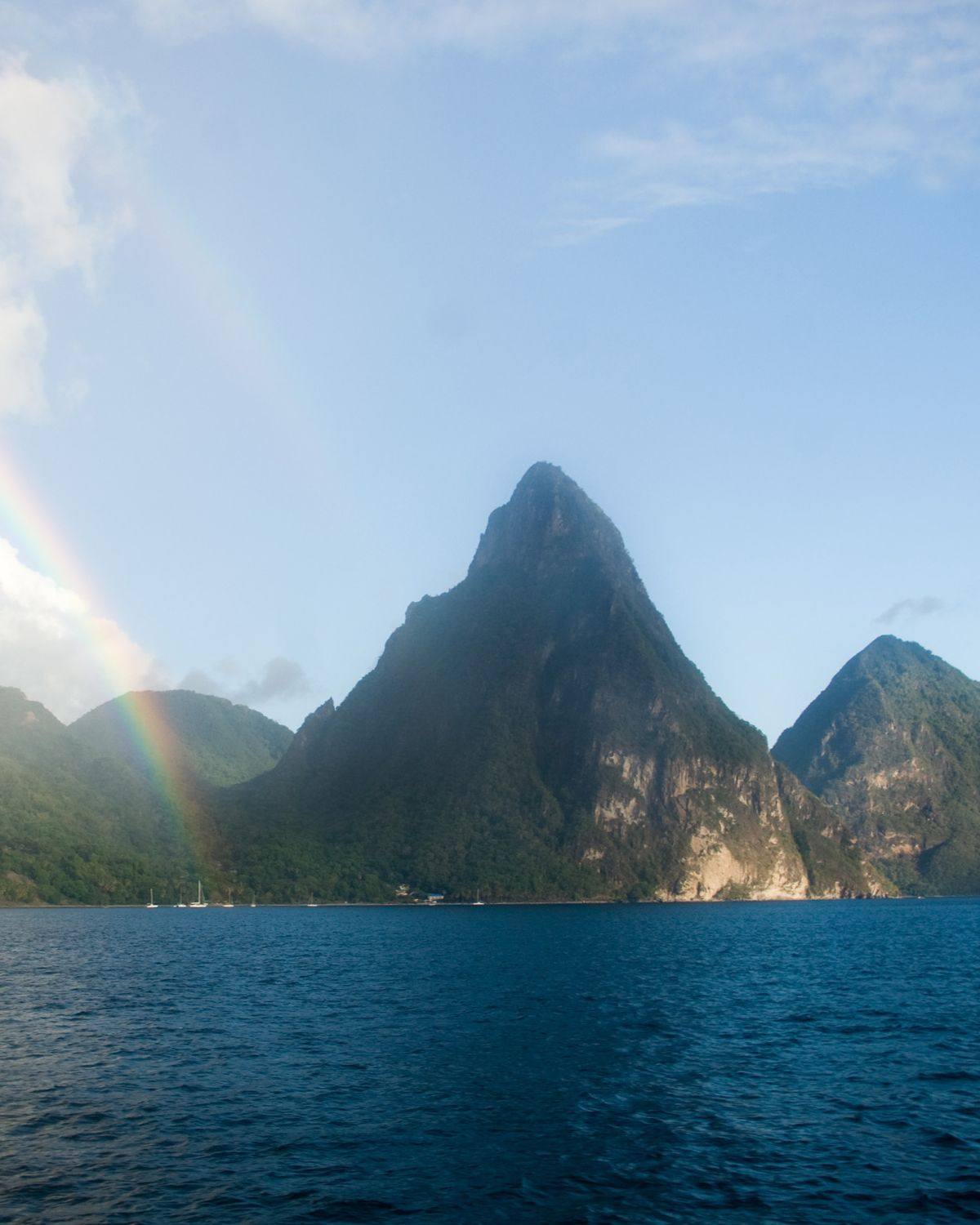 A rainbow dropping toward the sea beside Petit and Gros Piton, seen from the water