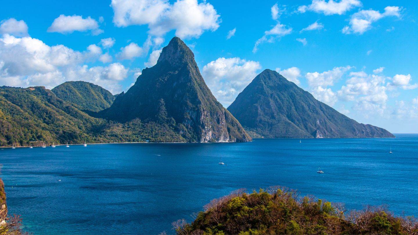 Gros and Petit Piton rising from the sea with yachts at anchor along the beach at their base