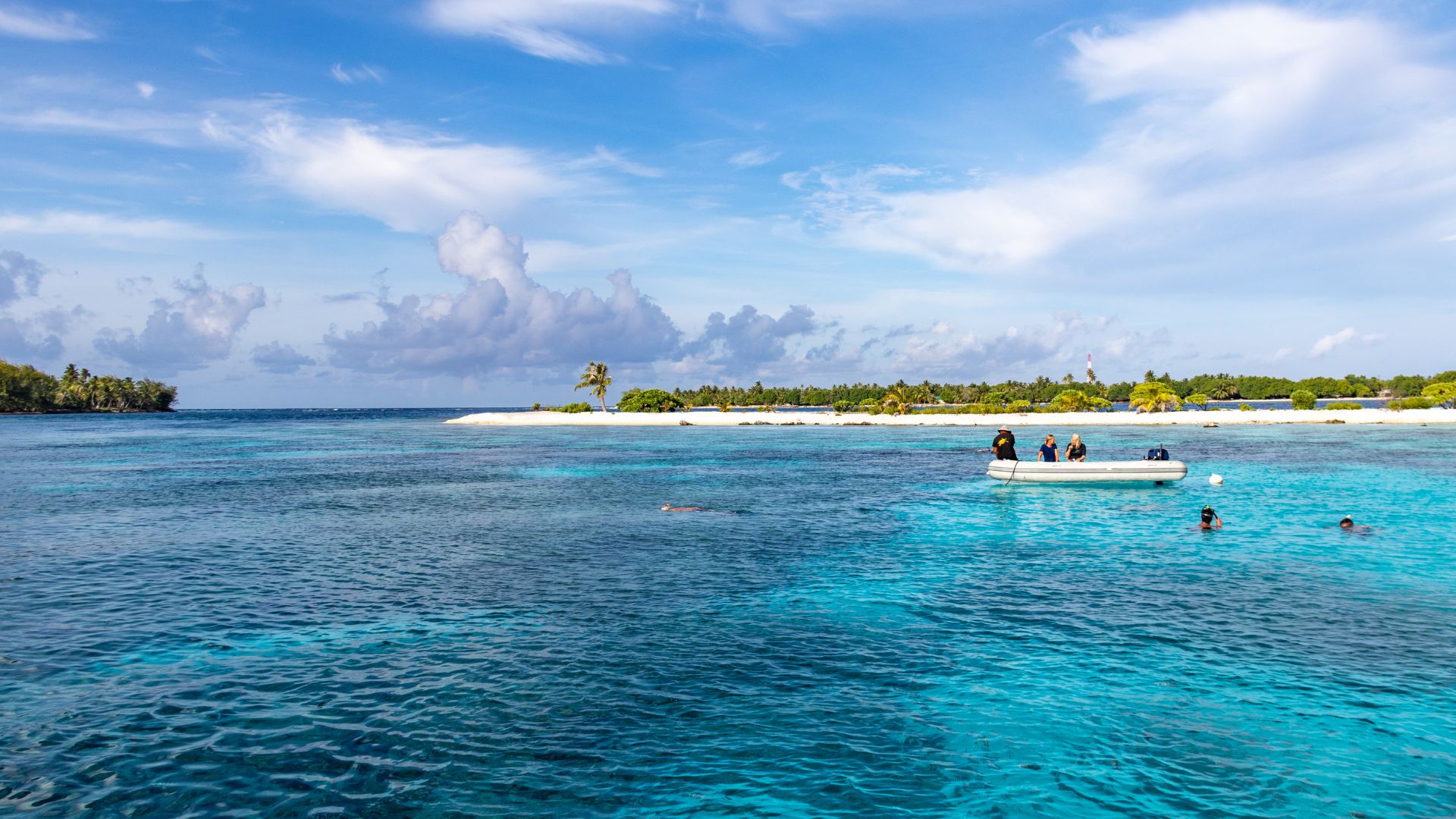 Surface side of the pass — snorkelers off the dinghy work the south-side coral garden while divers drift the pass wall a few hundred meters away. Almost everyone aboard finds something to do here.