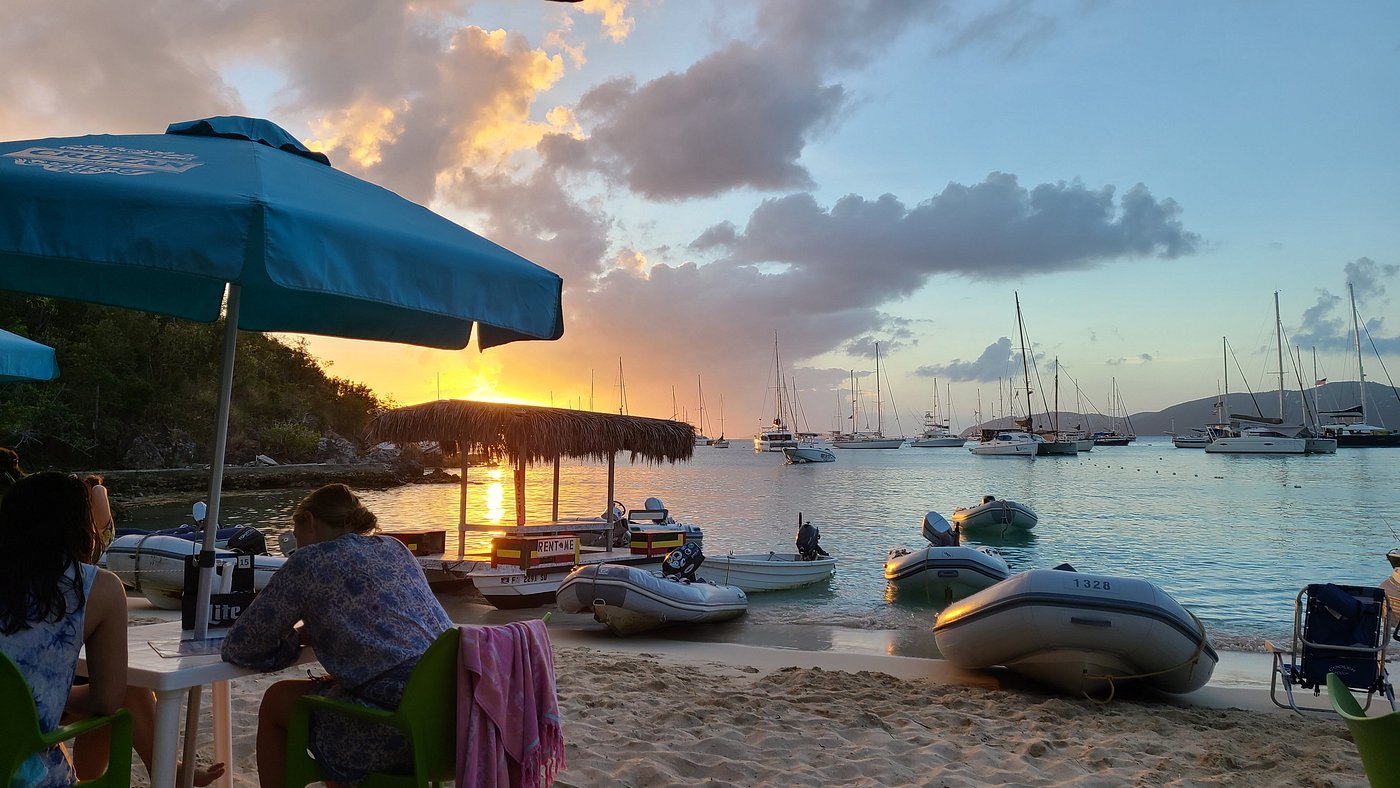 Dinghy's Beach Bar at Honeymoon Beach, Water Island — picnic tables buried in the sand, a steel band most afternoons. (Photo: Dinghy's Beach Bar)