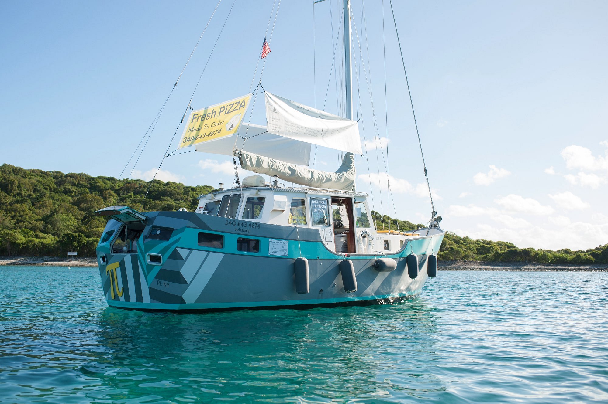 Pizza Pi — a 37-foot sailboat moored in Christmas Cove with a wood-fired oven on board. Order by radio; the boxes come over by tender, still warm. (Photo: Pizza Pi VI)