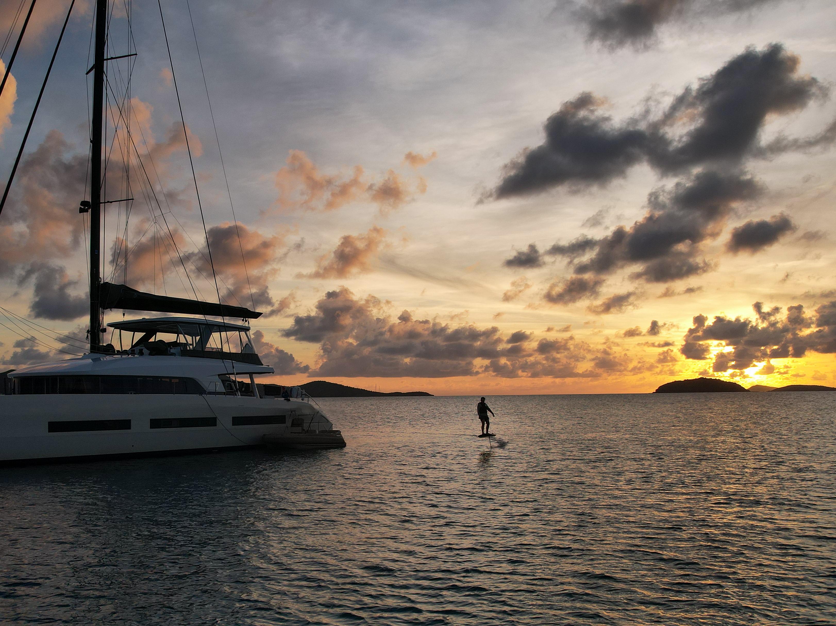 Sunset e-foiling next to a crewed catamaran in the US Virgin Islands
