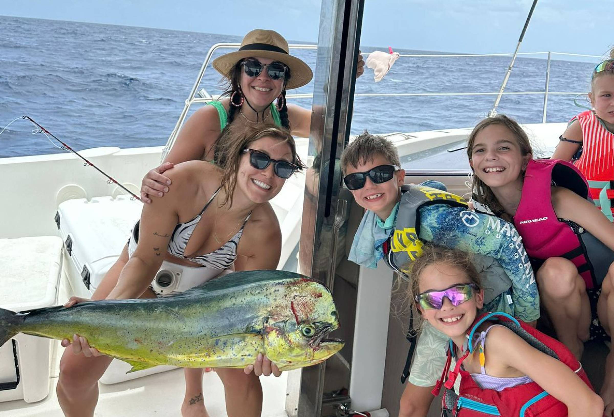 Kids showing off a mahi mahi catch on a family yacht charter
